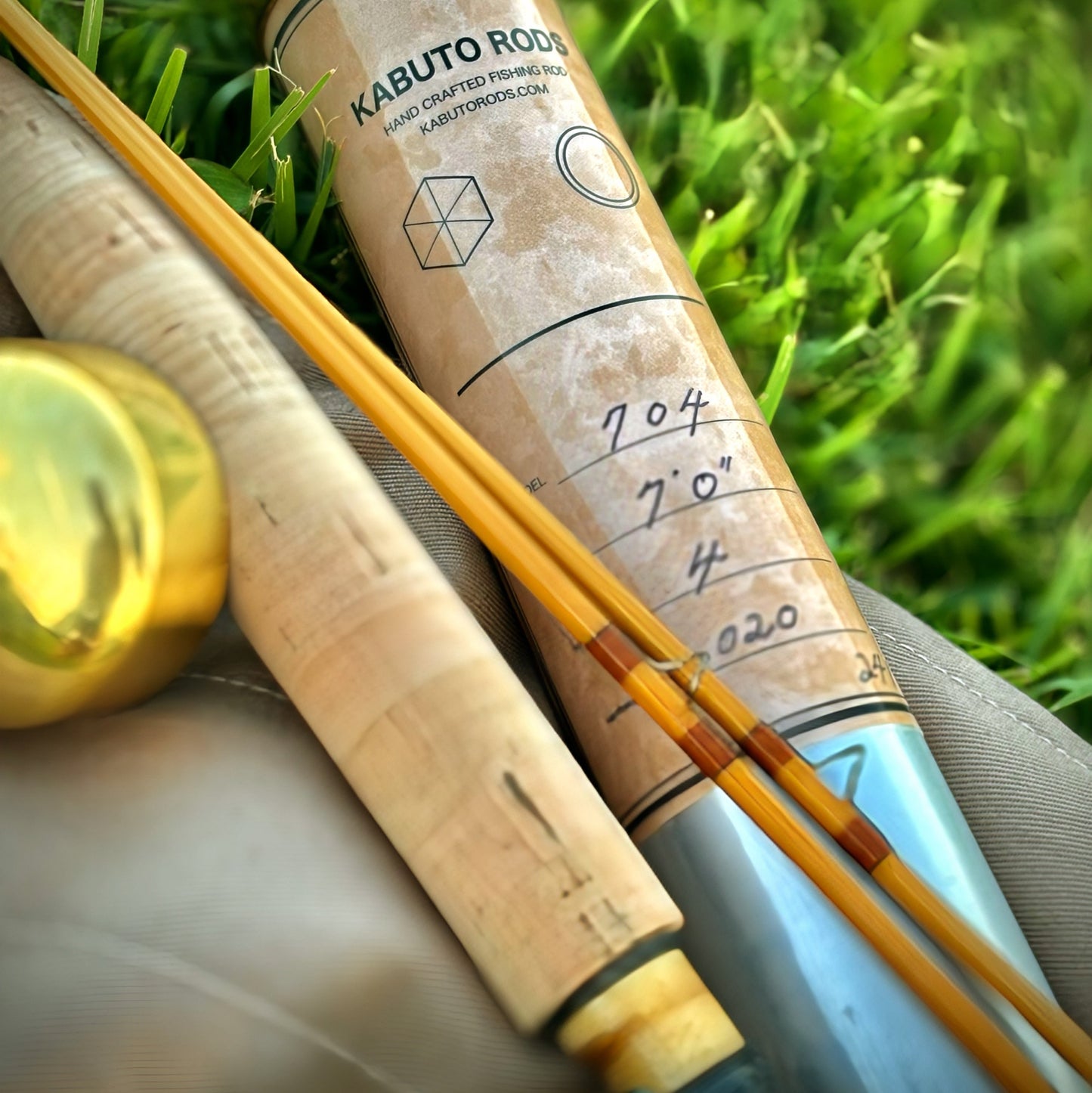 Fishing rod and reel on grass with 'Kabuto Rods' branding