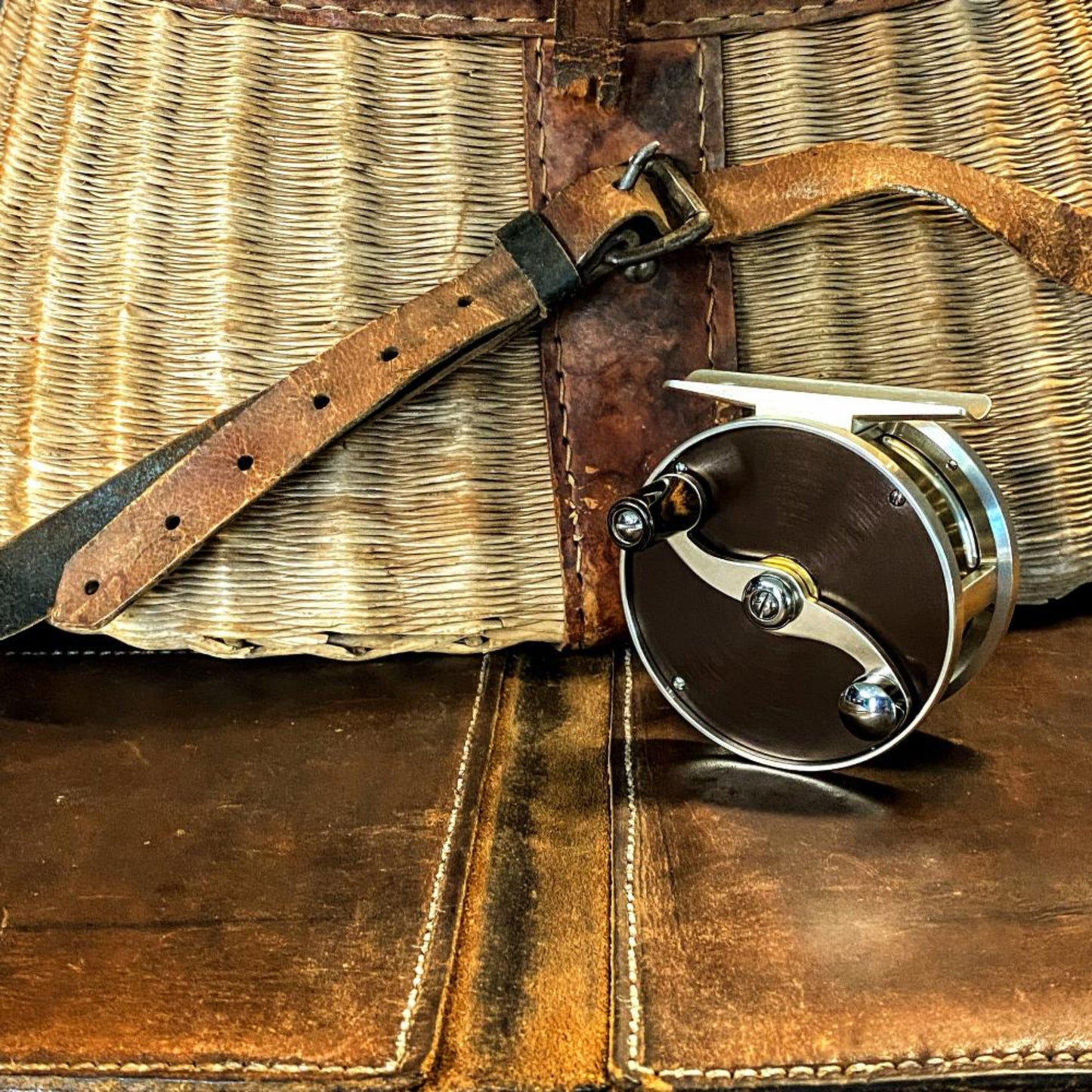 Handmade stainless steel S-handle with black and brown ebonite knob on Nikko Cobblestone trout reel - artisan craftsmanship detail