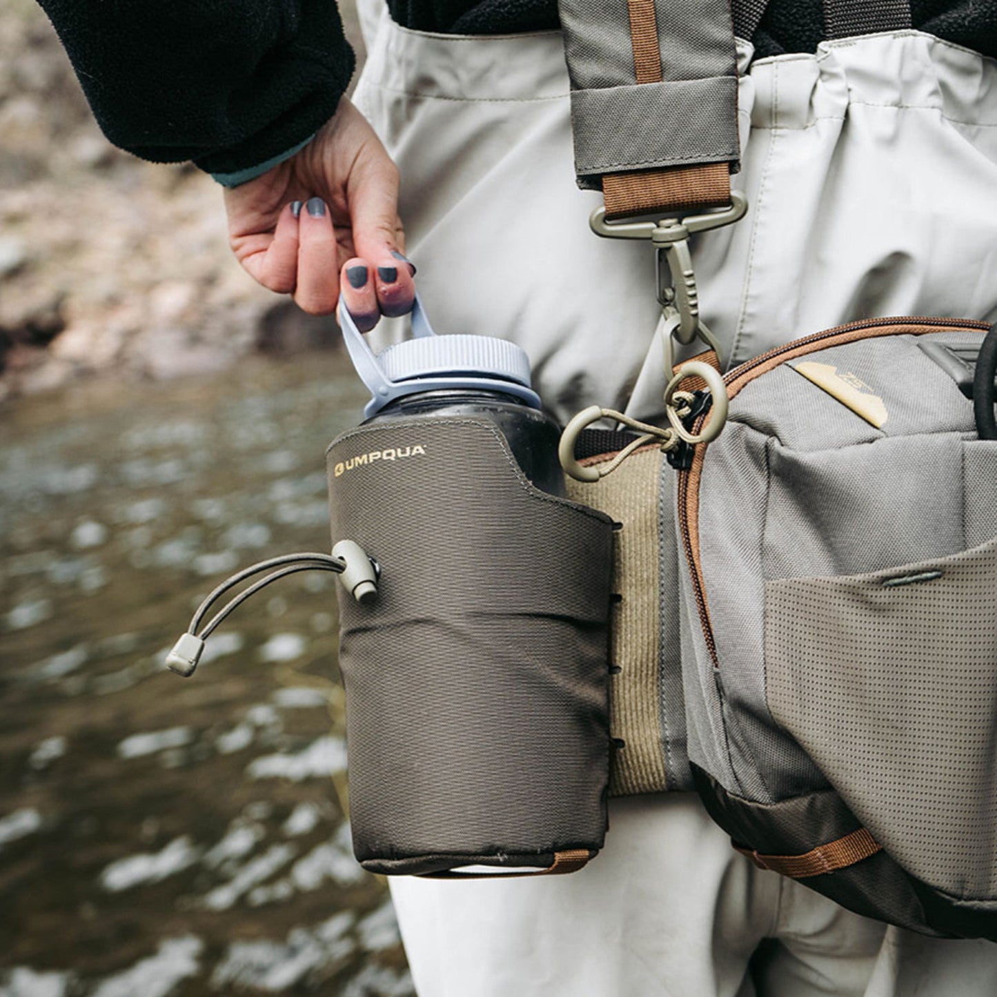 Will securely hold a wide range of water bottles and readily attach to many of our packs. Reinforced web loops with “Natick” snaps and Velcro back ensure secure attachment. Design allows for easy, one-hand access with adjustable, elastic security strap. Integrates seamlessly with the following packs:

a. Wader BeltZS2
b. Ledges ZS2 500 & 650 Waist Packs
c. Steamboat ZS2 Sling
d. Overlook ZS2 Chest Pack (to pack back)